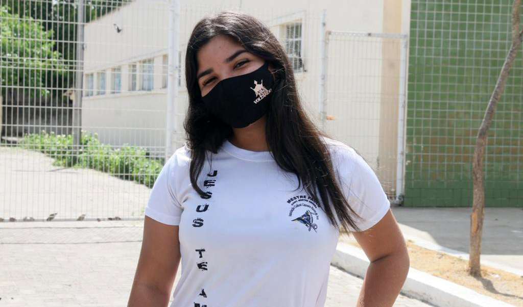 garota de máscara posando para a foto com roupa de capoeira